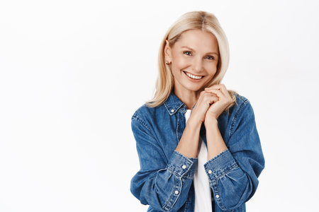 Aging beauty and skin care. Beautiful middle aged woman with blond hair, smiling and looking happy, posing in casual clothes, white backgroundの写真素材