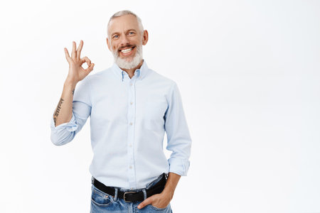 Image of businessman showing okay sign, ok gesture, approve, recommend something awesome, standing against white backgroundの写真素材