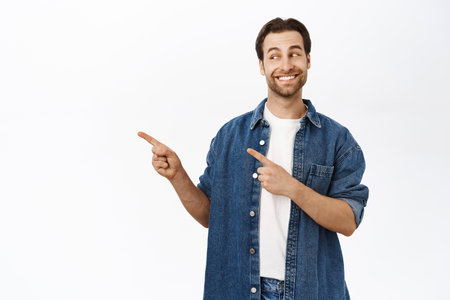 Portrait of handsome smiling adult man, pointing fingers left, showing way, promo on copy space, product banner, standing over white backgroundの写真素材