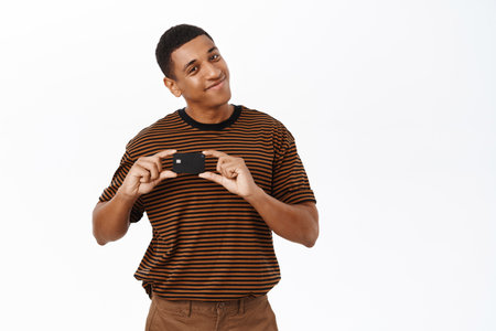 Smiling african american man shows his credit card. Concept of happy bank clientsの写真素材