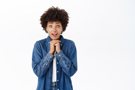 African american girl looks hopeful, looks with anticipation and temptation, smiling happy, standing over white backgroundの写真素材