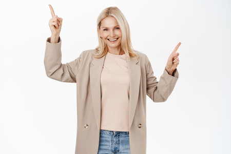 Portrait of beautiful middle aged woman pointing fingers left and right, showing direction, two variants, choices of products on sale, standing over white backgroundの写真素材