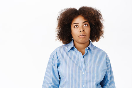 Portrait of african american woman roll eyes from boredom, looking bored and annoyed, standing over white backgroundの写真素材