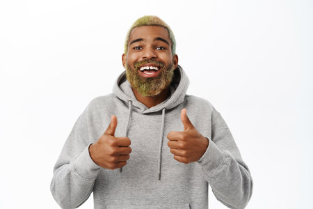 Enthusiastic black man with beard, smiling and laughing, showing thumbs up, approve something good, recommendingの写真素材