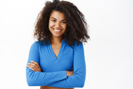 Portrait of beautiful young african american woman with shiny, curly healthy hair, posing happy, smiling, standing on white banner backgroundの写真素材