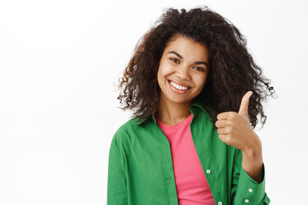 Cheerful girl shows thumb up in approval, like smth good, positive answer, saying yesの写真素材