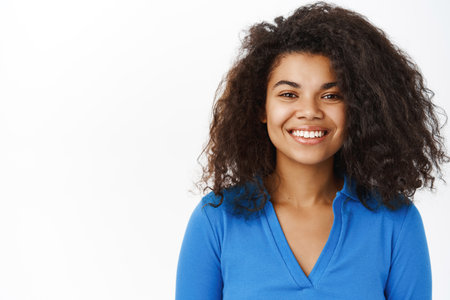 Haircare and beauty. Young curly black woman laughing, smiling, hair looks fresh and shiny, white smile, perfect skin without blemishes, studio backgroundの写真素材