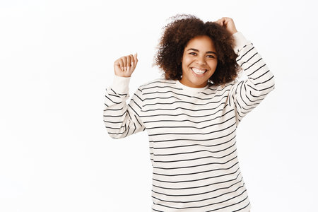 Portrait of happy african american woman dancing, feeling joy, standing over white backgroundの写真素材