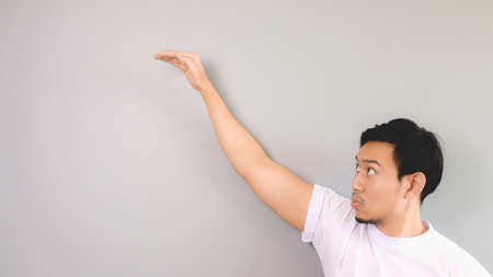 Very high hand sign. An asian man with white t-shirt and grey background.の写真素材