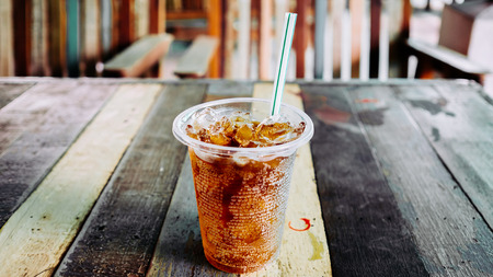 Plastic glass of cola on vintage table.