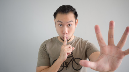Asian man is telling a secret. Do not tell anyone.の写真素材