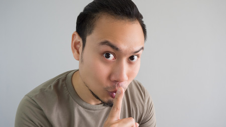 Asian man is telling a secret. Do not tell anyone.の写真素材