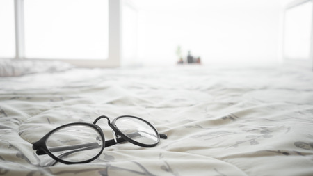Black eyeglasses on the bed.の写真素材
