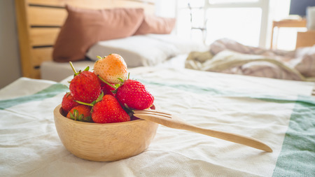 Strawberries in a bowl served in the bedroom with morning light.の写真素材