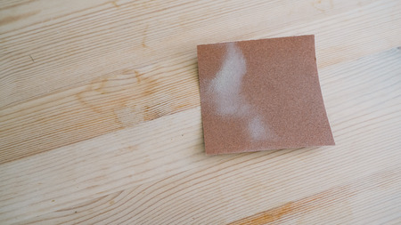 Cleaning stain on wooden table with sandpaper.