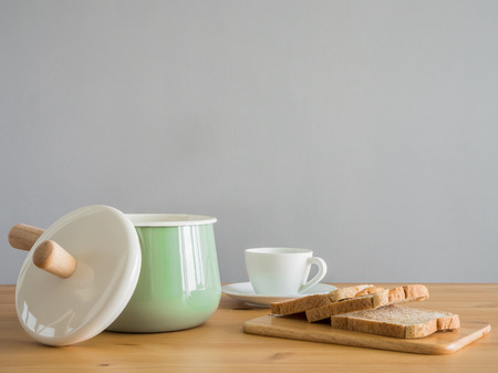 Wooden and stainless kitchenware on wooden table. Pastel utensil boiler with wooden handle.