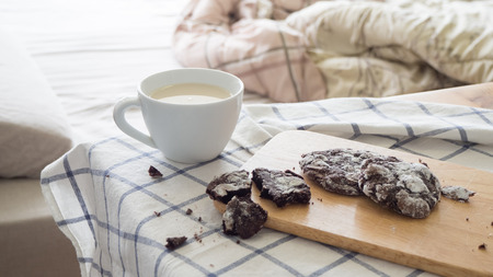 Chocolate chip cookies and a cup of milk on  wooden table with a blue kitchen cloth.の写真素材