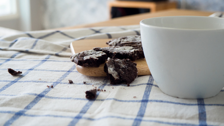 Chocolate chip cookies and a cup of milk on  wooden table with a blue kitchen cloth.の写真素材