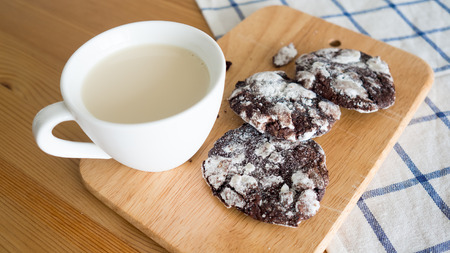 Chocolate chip cookies and a cup of milk on  wooden table with a blue kitchen cloth.