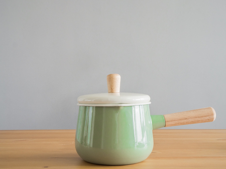 Wooden and stainless kitchenware on wooden table. Pastel utensil boiler with wooden handle.の写真素材