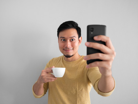 Asian man taking selfie while drinking coffee.の写真素材
