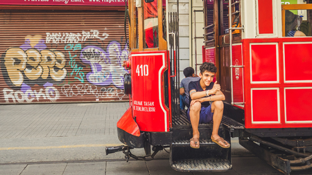 Istanbul, Turkey - September 13 2016: Turksih boy sitting on the tram and smiling to the tourist.のeditorial素材