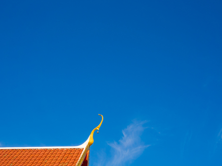Thai temple roof top on bright blue sky.の写真素材