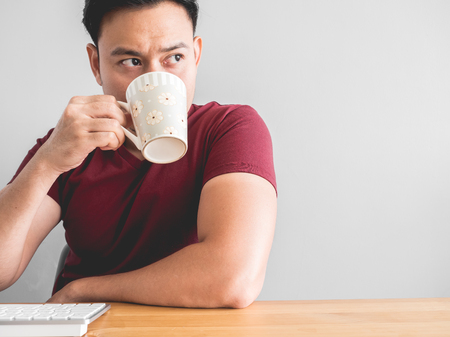 Asian man drink coffee on desk for work idea.の写真素材