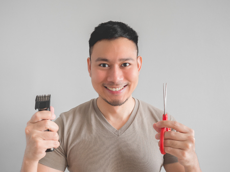 Asian man cut his own hair with clipper and scissor.の写真素材