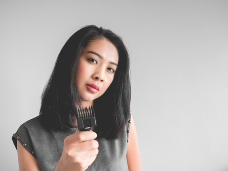 Asian woman wants to cut your hair with hair clipper.の写真素材