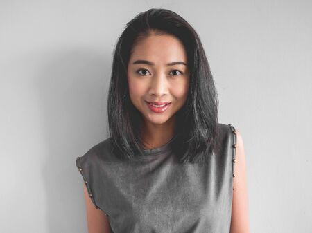Headshot of happy Asian woman in grey dress.の写真素材