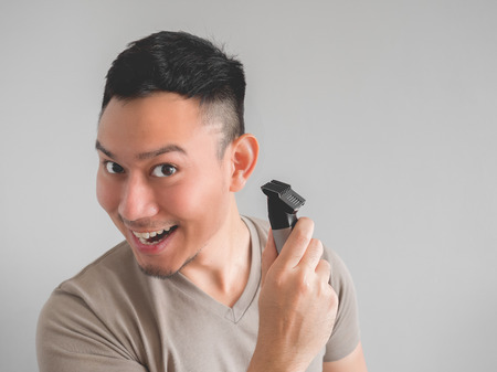 Asian man cut his own hair with clipper and scissor.