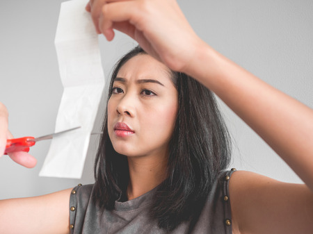 Asian woman plan to cut a bill into pieces.の写真素材
