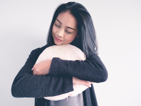 Asian woman hugging a cusion to keep warm and missing her lover.の写真素材