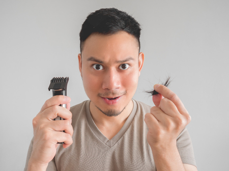 Asian man cut his own hair with clipper and scissor.の写真素材