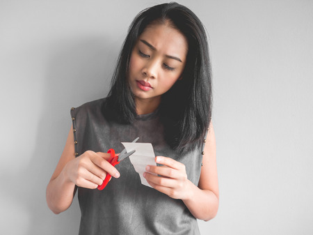 Asian woman plan to cut a bill into pieces.の写真素材