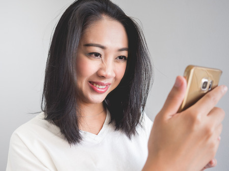 Asian woman look at smartphone and laugh.の写真素材