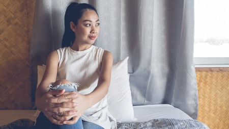 Asian woman relax in her bamboo bedroom with smartphone.の写真素材