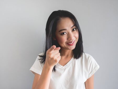 Asian woman make sly or cunning smile and hand point out as she know the secret.の写真素材