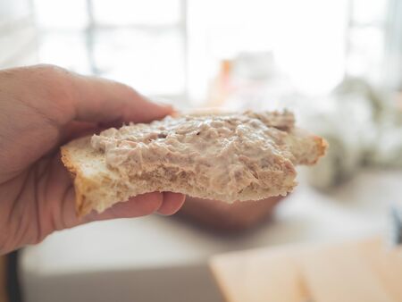 Eating tuna bread sandwich as breakfast in the morning.