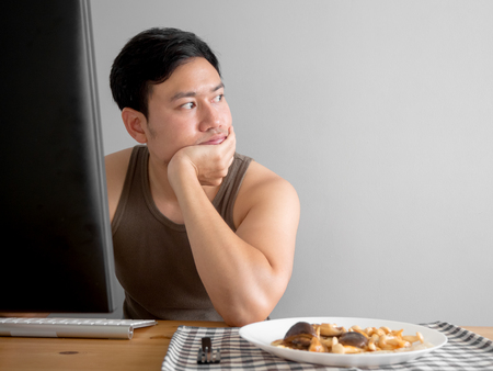 Asian man feel bored with his freelance work and his food.の写真素材