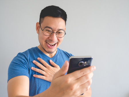 Happy Asian man using smarphone with shocked and surprised face expression.の写真素材