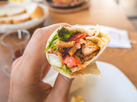 Close up of bitten doner chicken kebab in hand.の写真素材