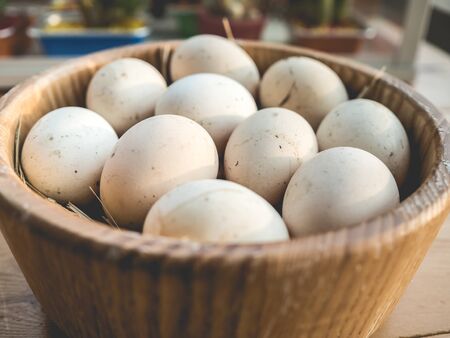 Fresh chicken eggs in a wooden bowl.