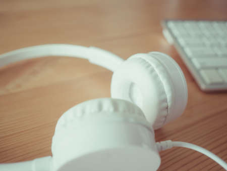 White headphone and keyboard on wooden desk.