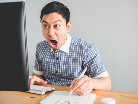 Asian man makes funny furious face as he speed up and tries to finish his work on time.の写真素材