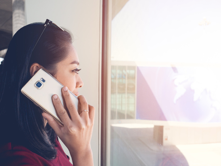 Asian woman use smartphone in the airport with morning sunlight.の写真素材