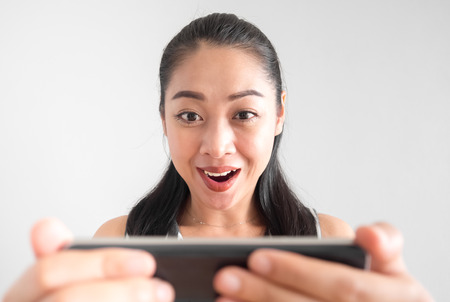 Shocked and surprised Asian woman using smartphone.の写真素材