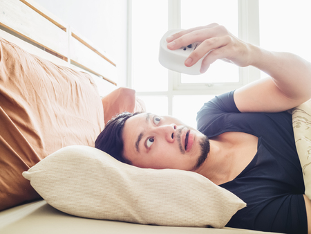 Funny face Asian man shocked as he wakes up late for an appointment.の写真素材