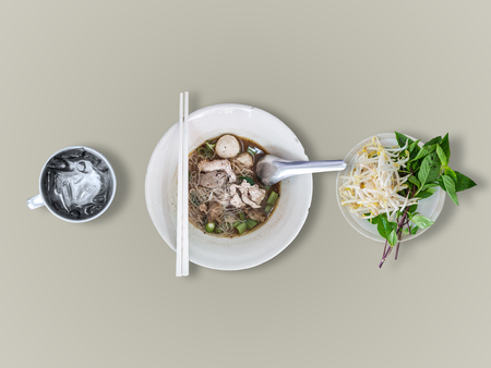 Top view of Thai rice noodles thicken soup with vegetables set and ice water cup.
